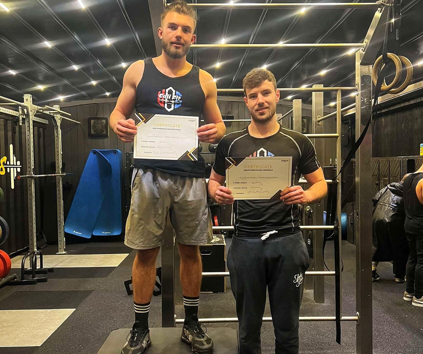 two Cali Fit members posing with certificates after winning a calisthenics competition