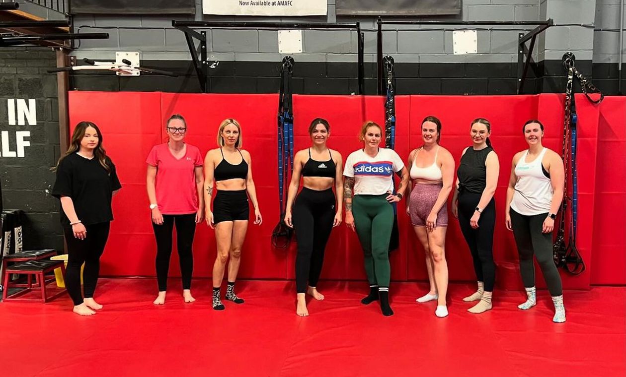 a calisthenics women-only class with a full club posing for a photo