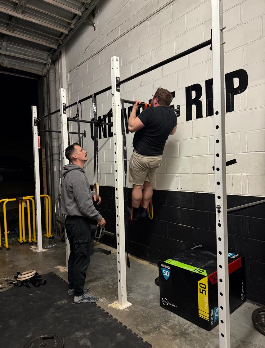 A calisthenics gym member doing a weighted pullup