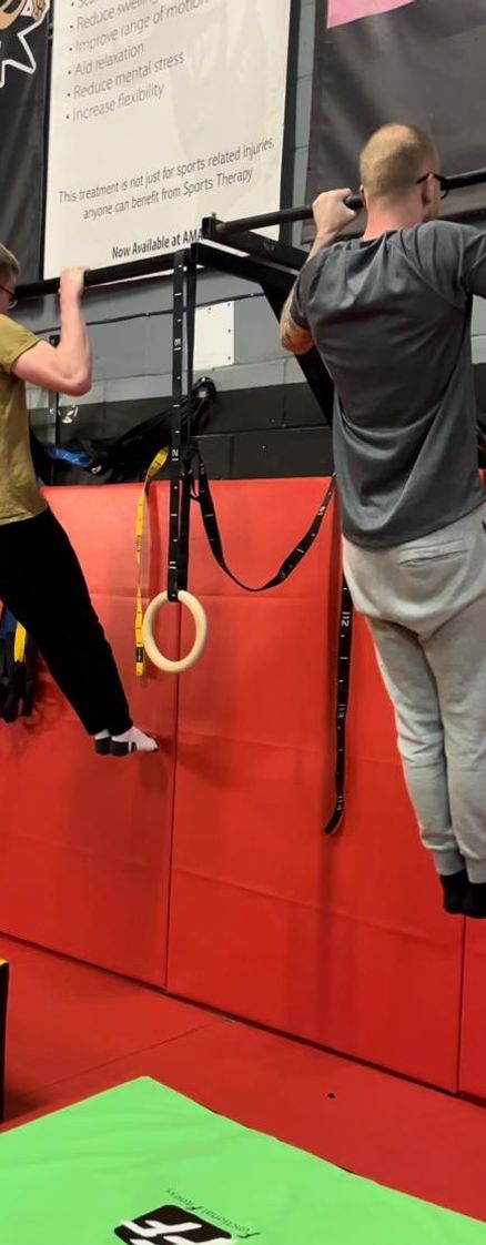 Two Cali Fit athletes competing in a pullup-hold challenge